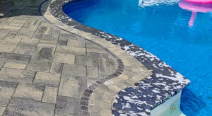 Closeup of curved area of inground pool surrounded by stone pavers