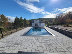 Inground pool surrounded by landscaping and stone pavers