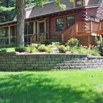 Stone block retaining wall in front of log home
