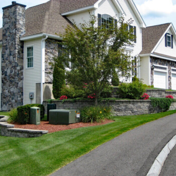 House exterior with block retaining wall with lush landscaping