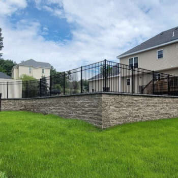 Raised patio area on a block wall with black fence