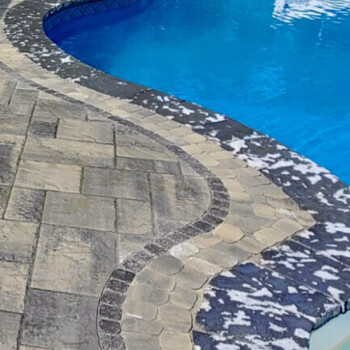 Closeup of curved area of inground pool surrounded by stone pavers