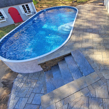 Above ground pool surrounded by stone pavers