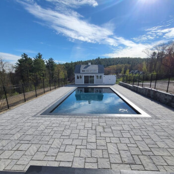 Inground pool surrounded by landscaping and stone pavers
