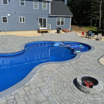 In ground pool with fire pit and stone paver patio