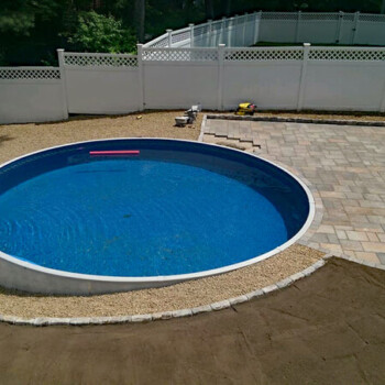 Round pool surrounded by stone paver patio
