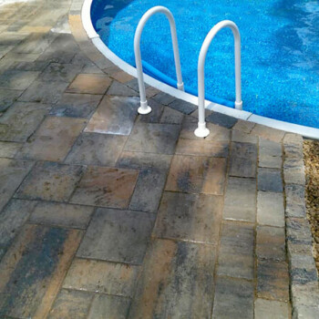 Closeup of pool ladder and pool with stone patio