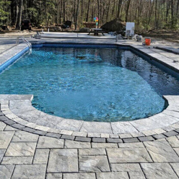 In ground pool surrounded by stone pavers